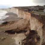 Falaise côtière fortement érodée au pied d’habitations